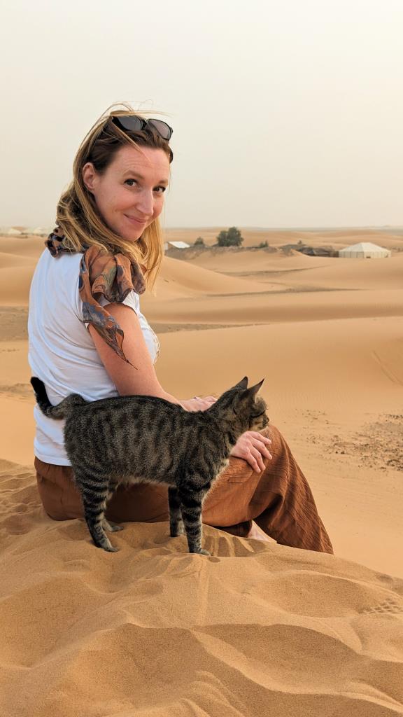 Fluppa nel deserto in Marocco seduta sulle dune che indossa t-shirt e pantaloni di cotone